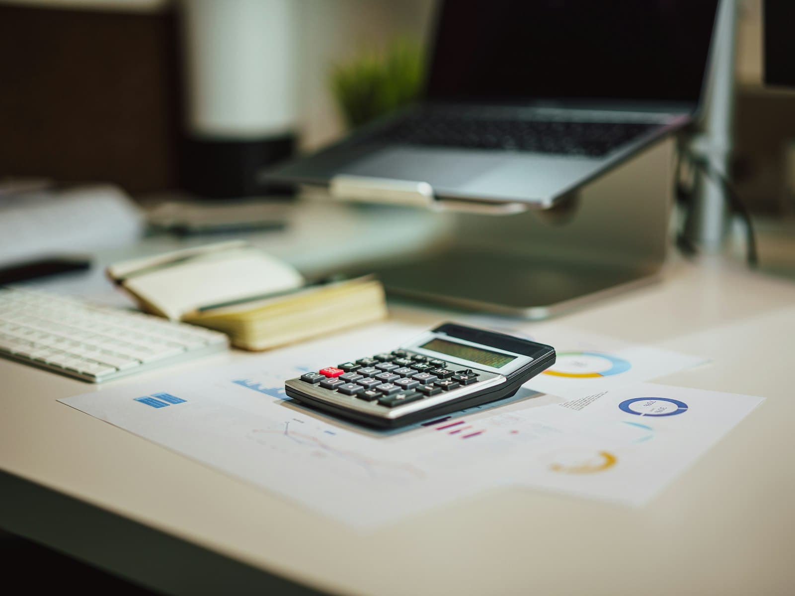 Calculator and laptop with financial charts on a modern desk